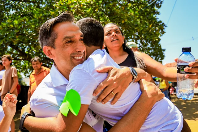 Fábio abraçando uma mulher à sombra de uma árvore.